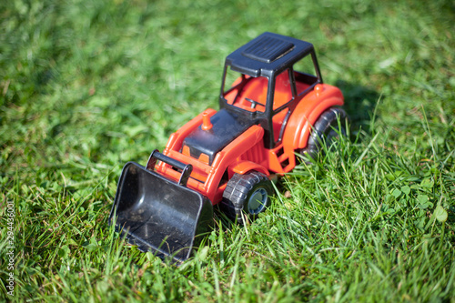 A tractor stands on the grass. Toy tractor on a green lawn. A toy for a child. Farming in miniature.
