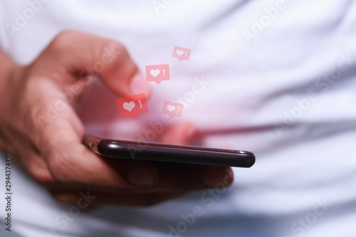 man's hand using smart phone with likes hovering over the screen  