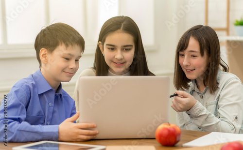 Happy pupils using laptop in school, watching videos © Prostock-studio