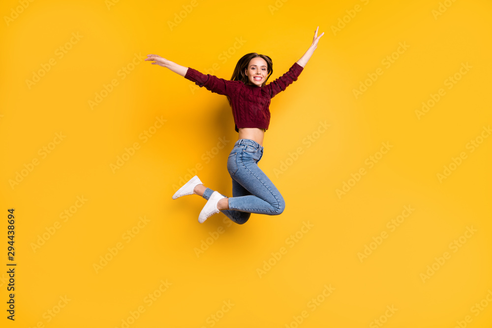 Full length photo of lovely girl smiling raising her arms smiling wearing marsala pullover isolated over yellow background