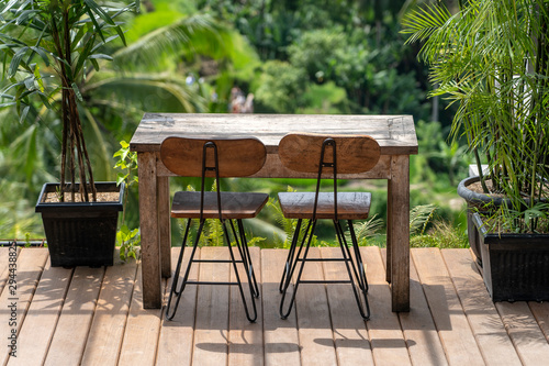 Wooden table and chairs in empty tropical cafe next to rice terraces in island Bali, Indonesia