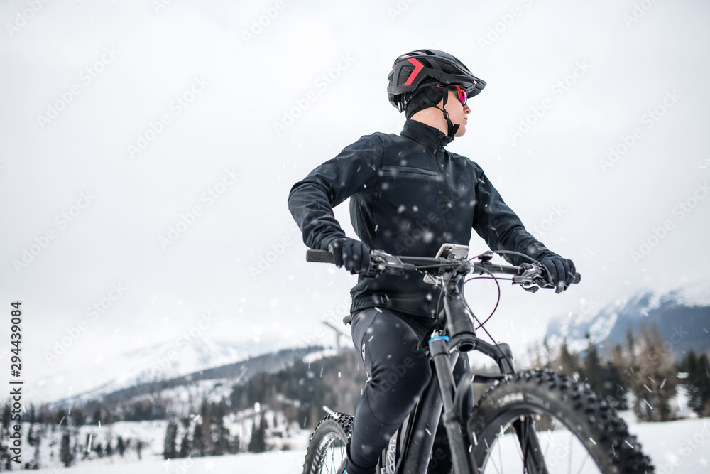 A mountain biker riding in snow outdoors in winter nature. A mountain biker riding in snow outdoors in winter nature.