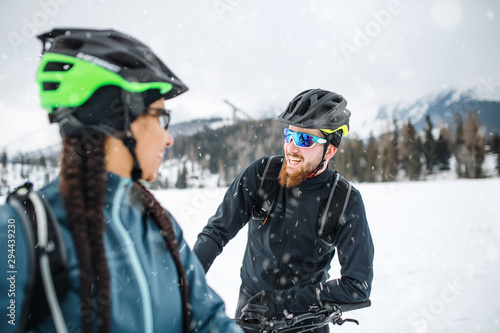 Two mountain bikers with bicycles on road outdoors in winter, talking.