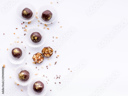 Confectionery pattern. Top view handmade chocolates with peanuts and honey. Gourmet chocolates on a white background. Close-up. Soft focus. Copy space