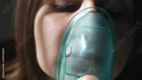 Use a nebulizer and inhaler for treatment. Young woman inhaling inhaler through a mask