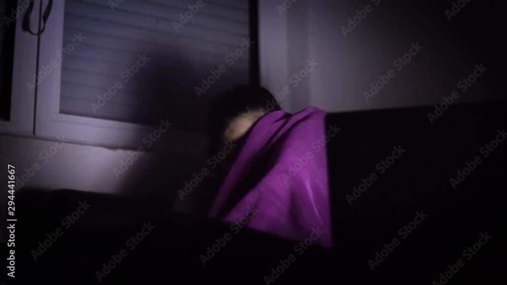 Teen girl is scared and hiding behind the blanket during horror movie Teen girl is scared and hiding behind the blanket during horror movie
