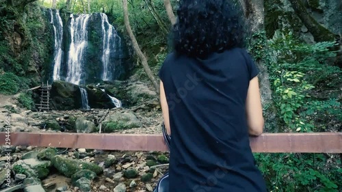 Woman with curly hair enjoying the view of the waterfall photo