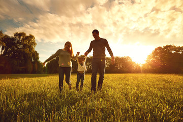 Happy family walks on the park at sunset.