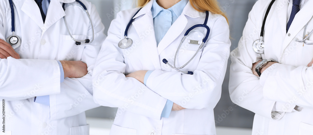 Group of modern doctors standing as a team with arms crossed in hospital office, close-up. Physicians ready to examine and help patients. Medical help, insurance in health care, best treatment and Group of modern doctors standing as a team with arms crossed in hospital office, close-up. Physicians ready to examine and help patients. Medical help, insurance in health care, best treatment and