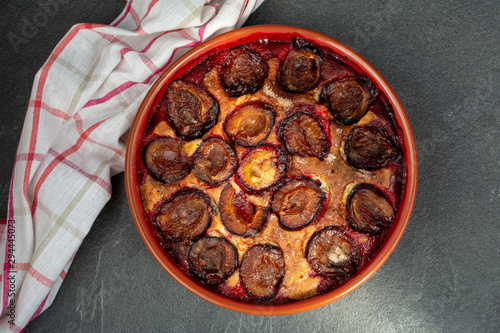 Original plum torte NYT's recipe. Homemade pie with halves of fresh plums in ceramic shape. photo