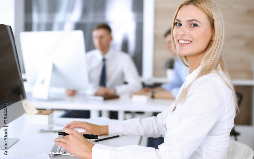 Obraz premium Business woman using computer at workplace in modern office. Secretary or female lawyer smiling and looks happy. Working for pleasure and success
