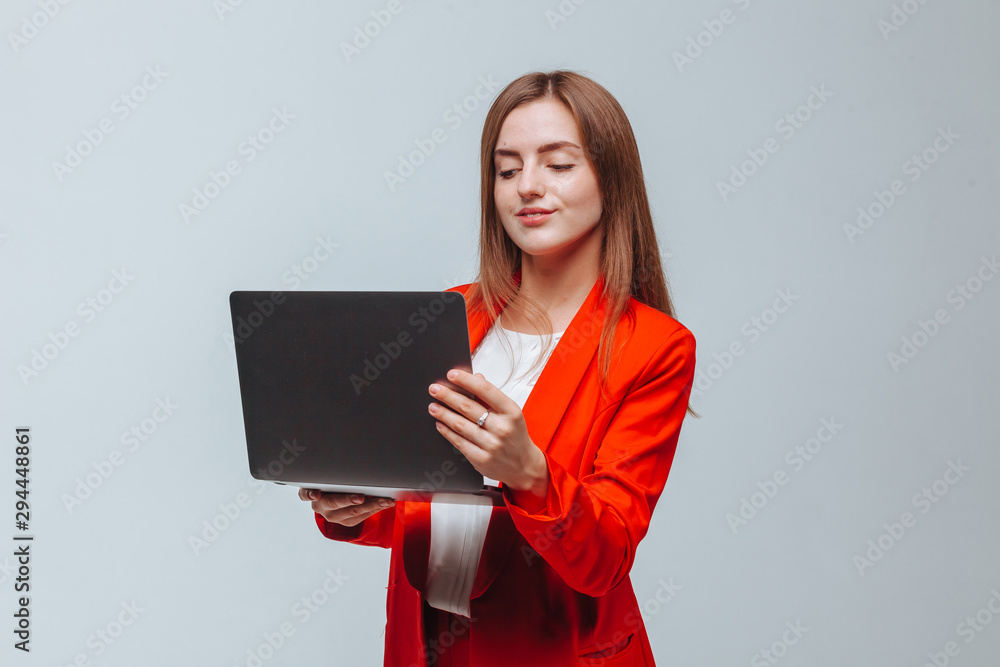 Obraz premium girl in a red jacket holds a laptop on a light background