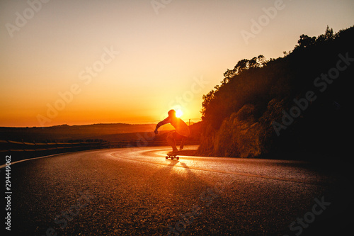 Skater descending a road at sunset