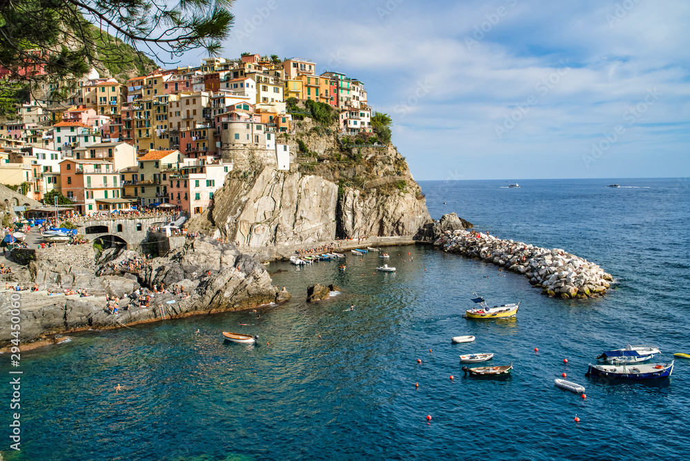 Manarola, Cinque Terre, Italy - August 17, 2019: Picturesque village in the province of La Spezia. Colorful houses on the coastal cliffs. Ligurian Sea Bay with moored boats