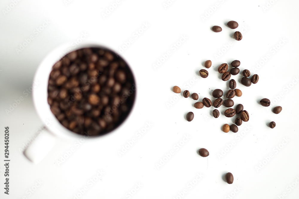 Obraz premium Coffee beans are sprinkled on the table next to a cup of coffee beans.