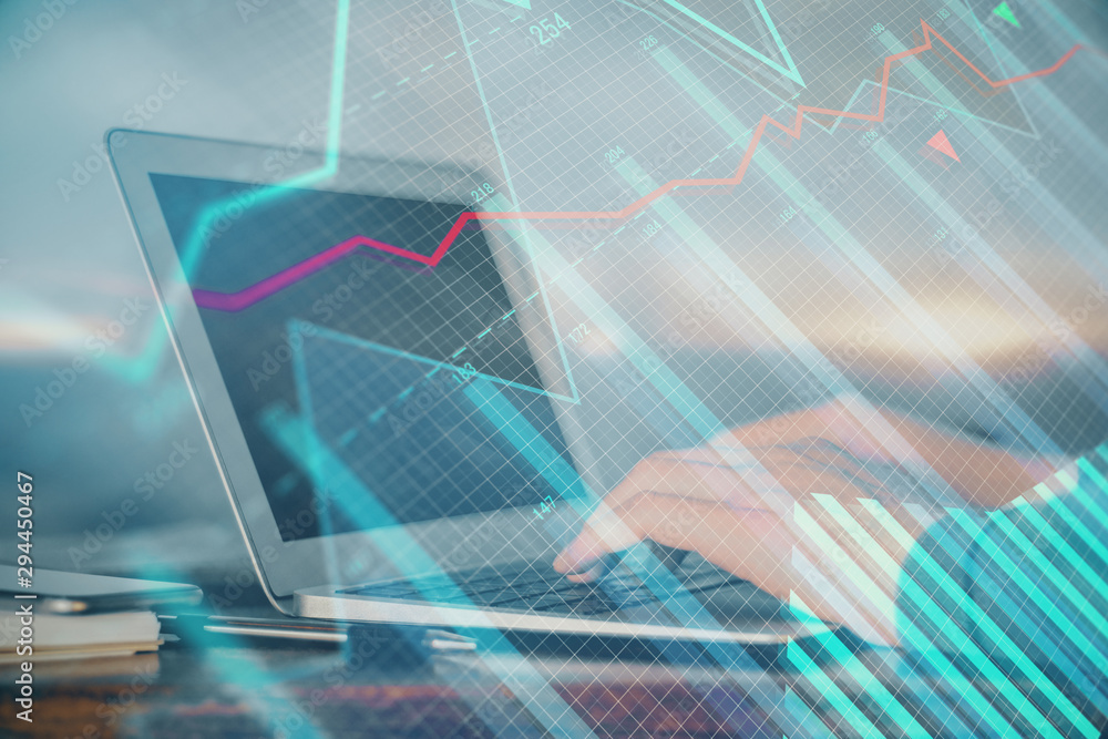 Double exposure of man's hands writing notes with laptop of stock market with forex graph background. Top View. Concept of research and trading. Double exposure of man's hands writing notes with laptop of stock market with forex graph background. Top View. Concept of research and trading.