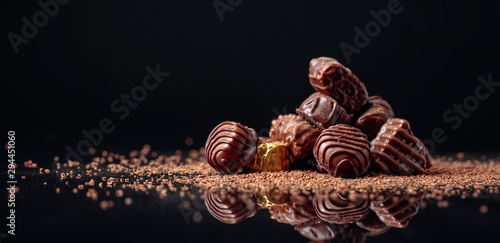Bild auf Leinwand Chocolate candies on a black background sprinkled with chocolate chips