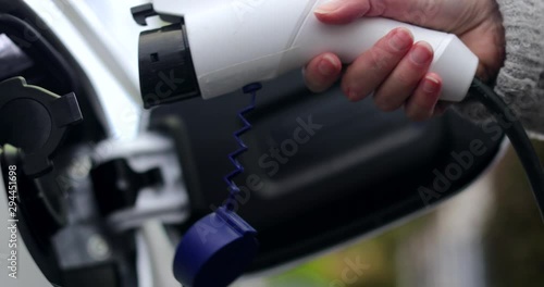 Close Up Of Hand Attaching Power Cable To Environmentally Friendly Zero Emission Electric Car 