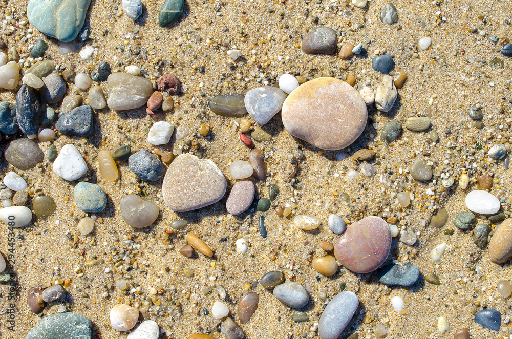 Pebble beach. Small colored sea stones close-up. Multicolor seabed. Selective focus image, copy space. Sea beach backdrop. Summer holiday concept.