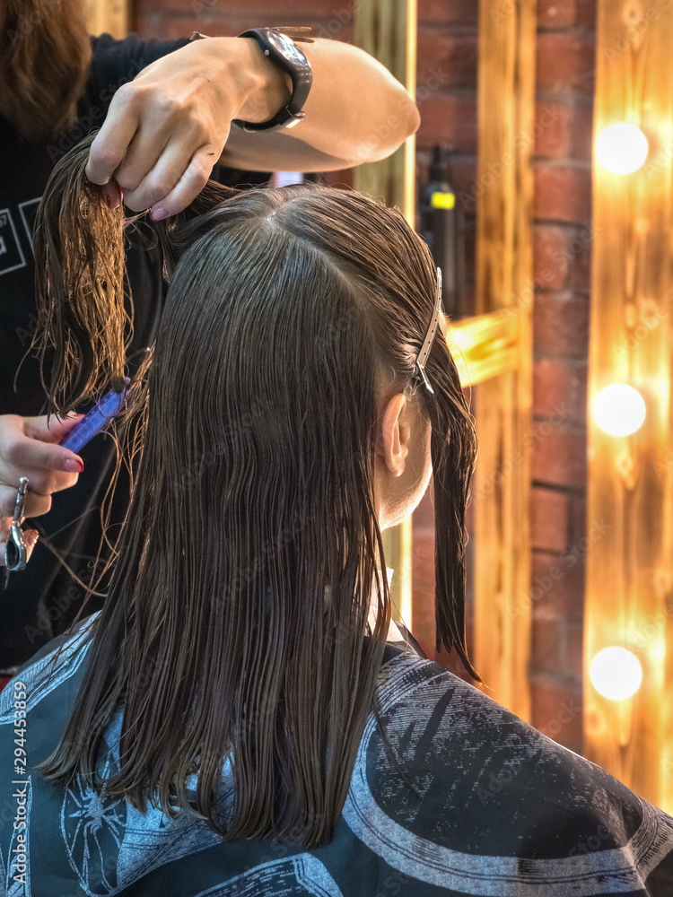 Fototapeta premium Woman is having her hair cut in on a dark background.