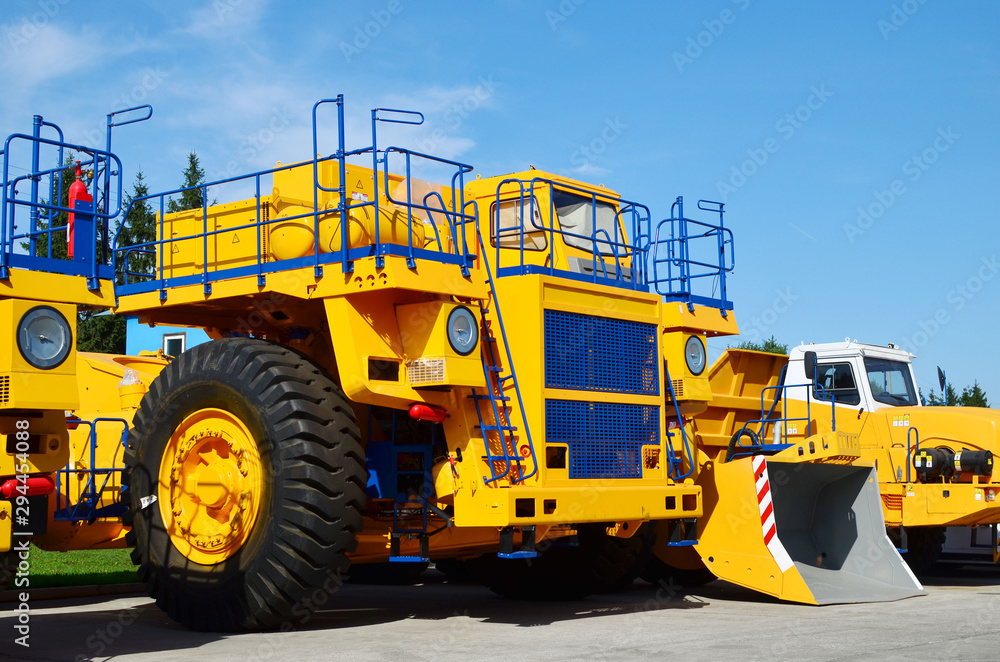 Heavy-duty trucks warehouse at autoworks. Giant mining dump trucks manufacture by the heavy vehicle plant. Heavy quarry equipment. Coal mining, granite, gravel, sand.