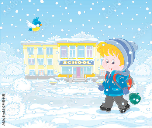 Winter morning, a smiling schoolboy with his schoolbag going to school through snowfall, vector illustration in a cartoon style