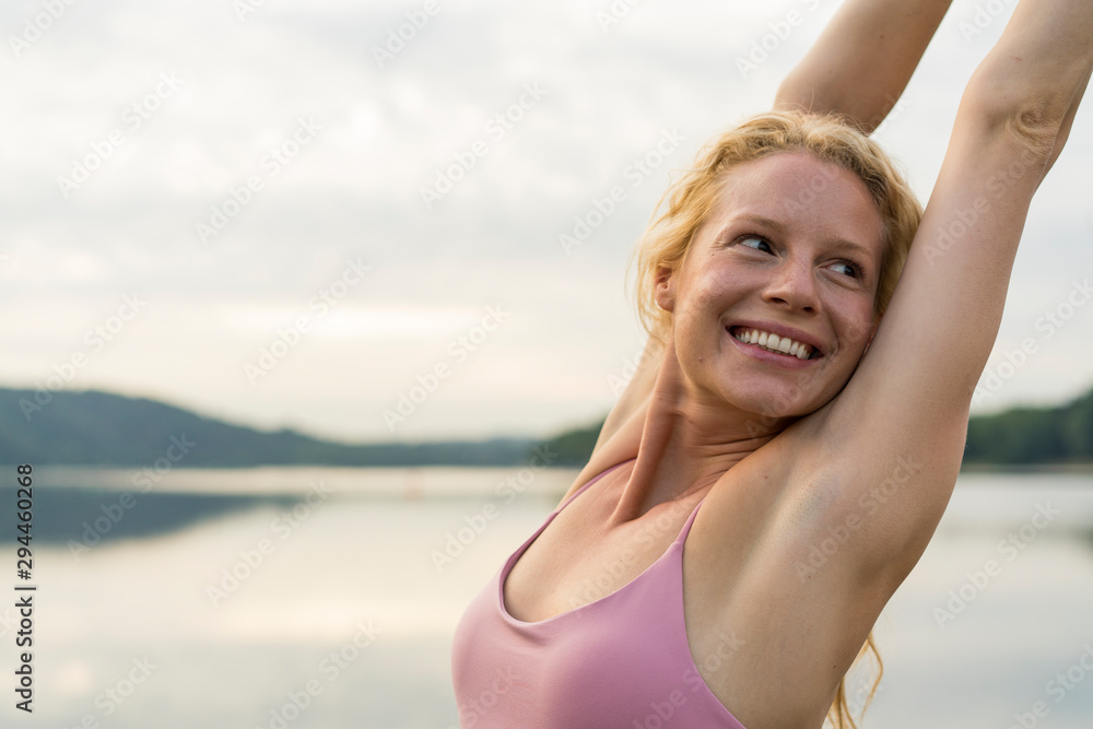 Happy young woman raising her arms at a lake Happy young woman raising her arms at a lake