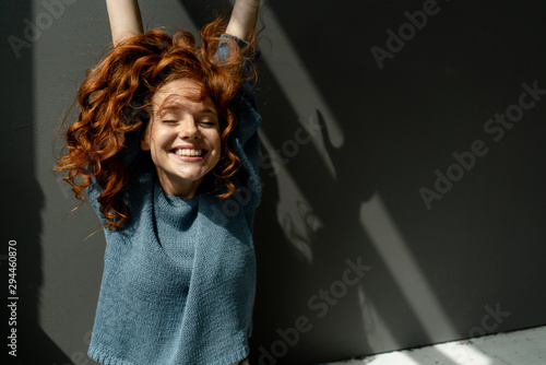 Portrait of happy redheaded woman with eyes closed raising hands