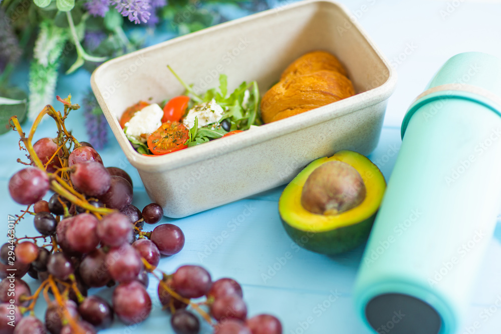 Close up of plastic container with healthy school lunch, thermos and grape on table. Close up of plastic container with healthy school lunch, thermos and grape on table.