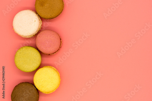 delicious macarons arranged in a row on pink background with copy space