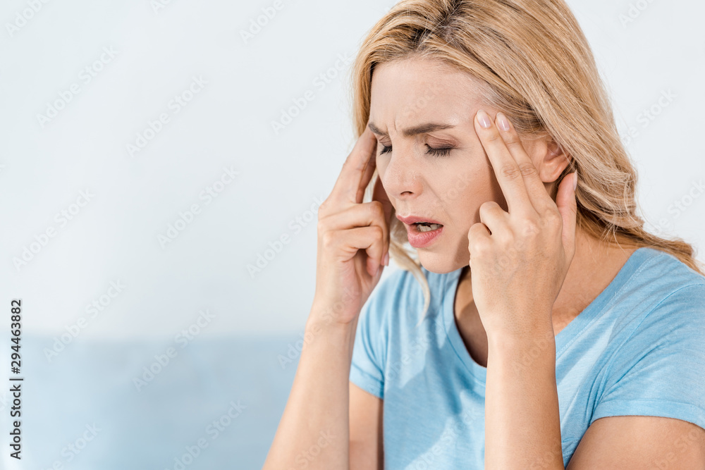 tired woman having migraine and touching temples at home tired woman having migraine and touching temples at home