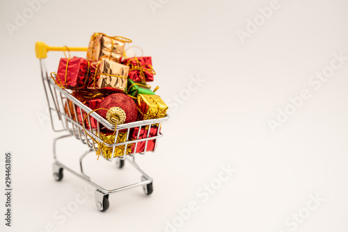 New Year's gifts and toys in supermarket trolley on white background. Christmas shopping concept