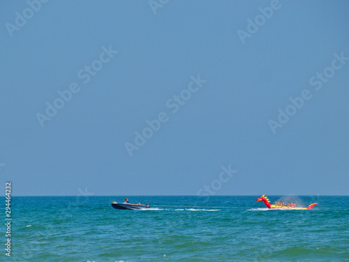 O sea ​​attraction red and yellow dragon-shaped inflatable boat with people sitting on it and towed by a motor boat