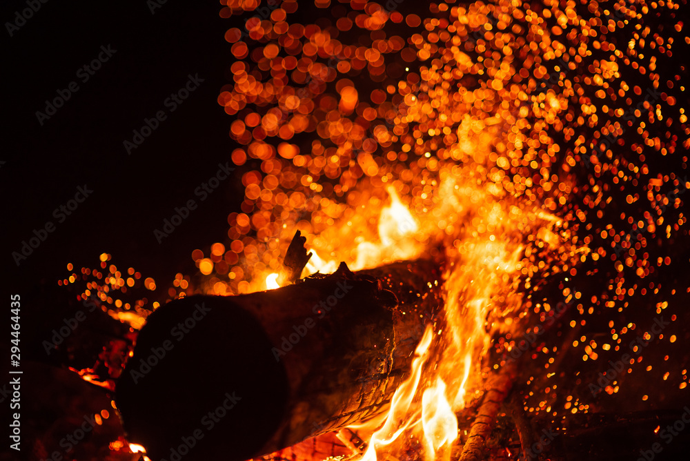 Beautiful abstract background on the theme of fire, light and life. Burning  red hot sparks fly from large fire in the night sky. Burning embers glowing  flying over black background. Stock Photo |