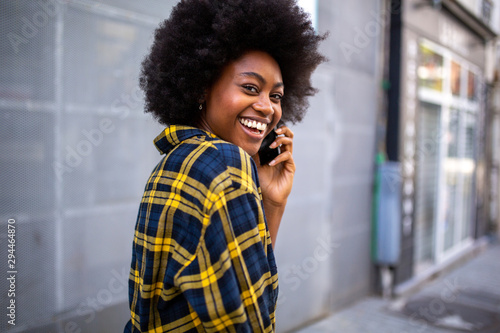 cheerful young black woman turning around talking with mobile phone
