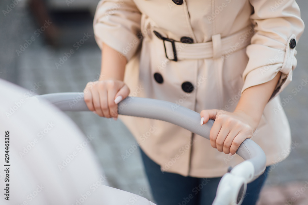 Close up photo, woman hands holding baby stroller.