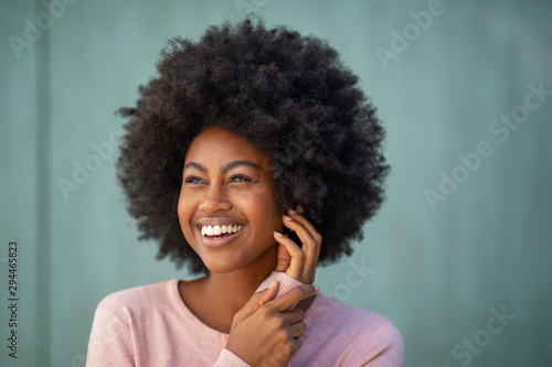 Close up young african american woman with afro smiling and hand on face