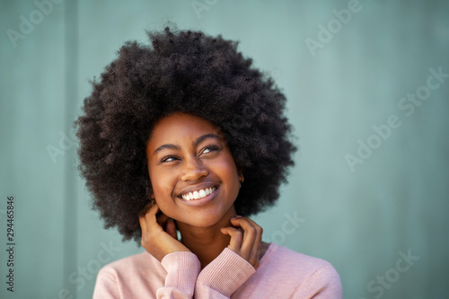 beautiful young black woman smiling with hands by face and looking away