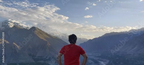 Person standing and facing back on mountain