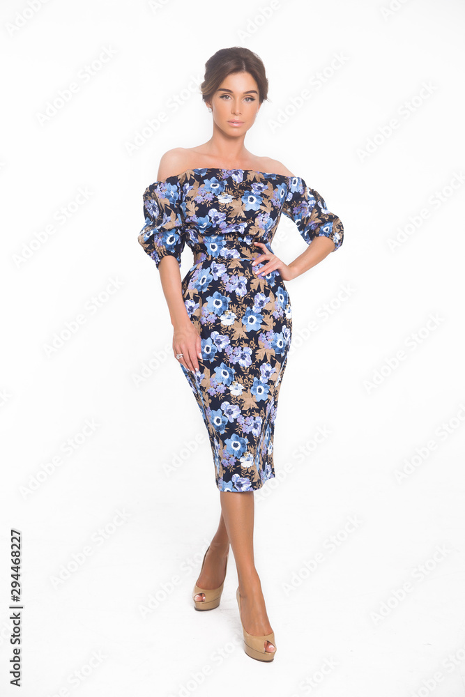 Beautiful elegant young woman with fashion hairstyle and makeup posing on a white background on high heels isolated in a floral dress. Free space for text mockup Beautiful elegant young woman with fashion hairstyle and makeup posing on a white background on high heels isolated in a floral dress. Free space for text mockup