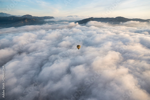A hot air balloon flies over a sea of clouds in the region of La Garrotxa, in Girona (Spain) at dawn.