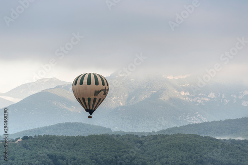 A hot air balloon flies over a sea of clouds in the region of La Garrotxa, in Girona (Spain) at dawn.
