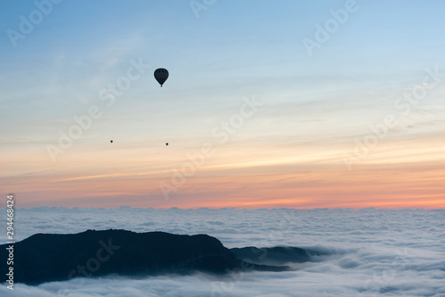 A group of hot air balloons flies over a sea of clouds in the region of La Garrotxa, in Girona (Spain) at dawn.