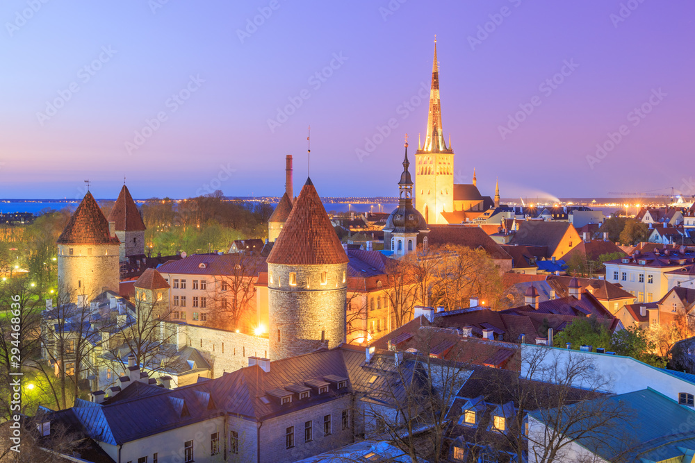 Obraz premium Historical old town of Tallinn, Estonia illuminated at night, after sunset, under a beautiful clear and colorful, purple and pink dusk sky. Aerial view.