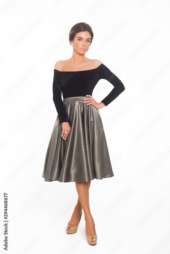 Beautiful elegant young woman with fashion hairstyle and makeup posing on a white background on high heels isolated in a black blouse and satin skirt. Free space for text mockup