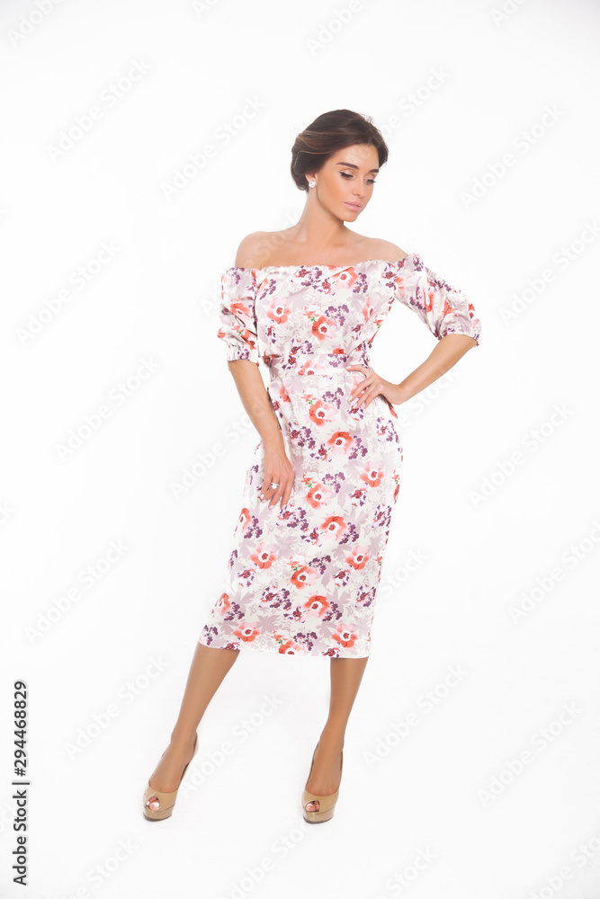 Beautiful elegant young woman with fashion hairstyle and makeup posing on a white background on high heels isolated in a floral dress. Free space for text mockup Beautiful elegant young woman with fashion hairstyle and makeup posing on a white background on high heels isolated in a floral dress. Free space for text mockup