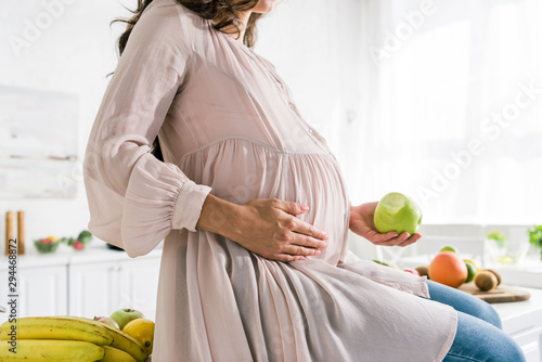 cropped view of pregnant woman holding apple photo