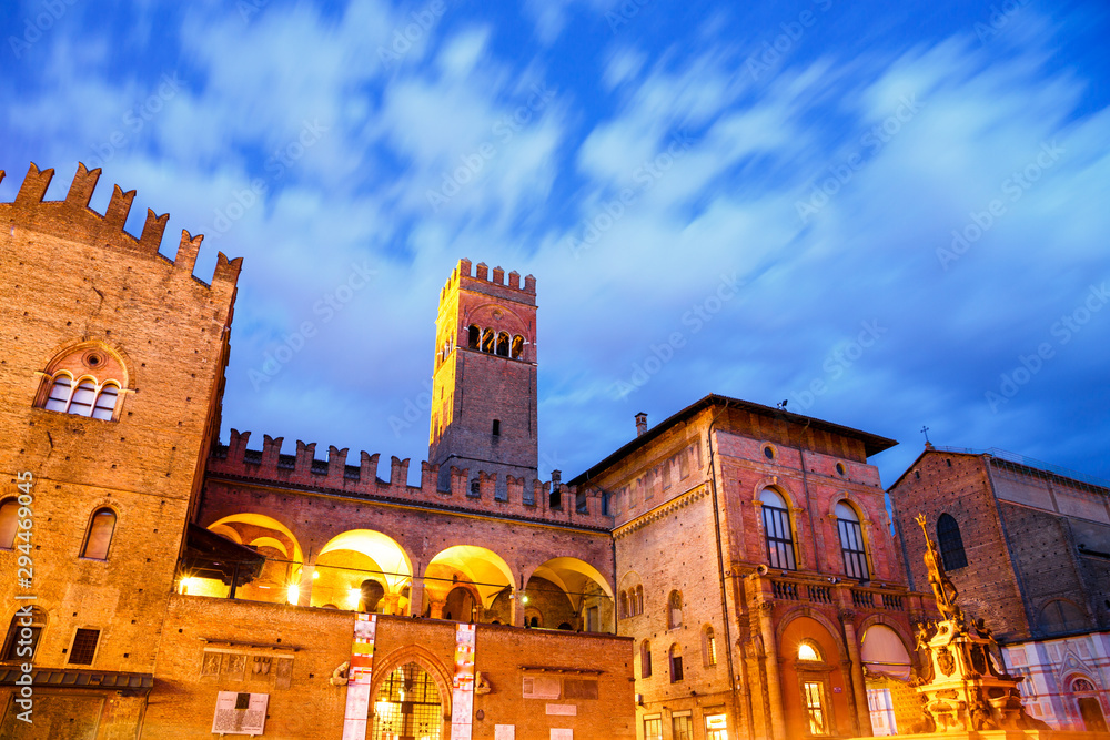 Bologna, Italy by night. Illuminated Palazzo Re Enzo at dusk, under dramatic sky with blurred clouds in motion.