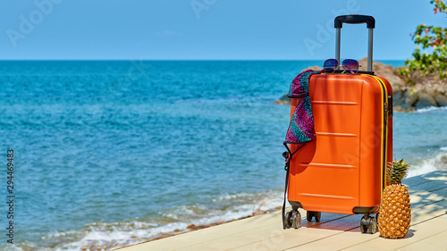 Turquoise sea  orange suitcase  sunglasses  swimsuit. Relax started.