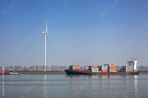 Netherlands, New Waterway. Container ship in front of modern windmill shipping, transport and heavy industry nera Maasvlakte 2. photo